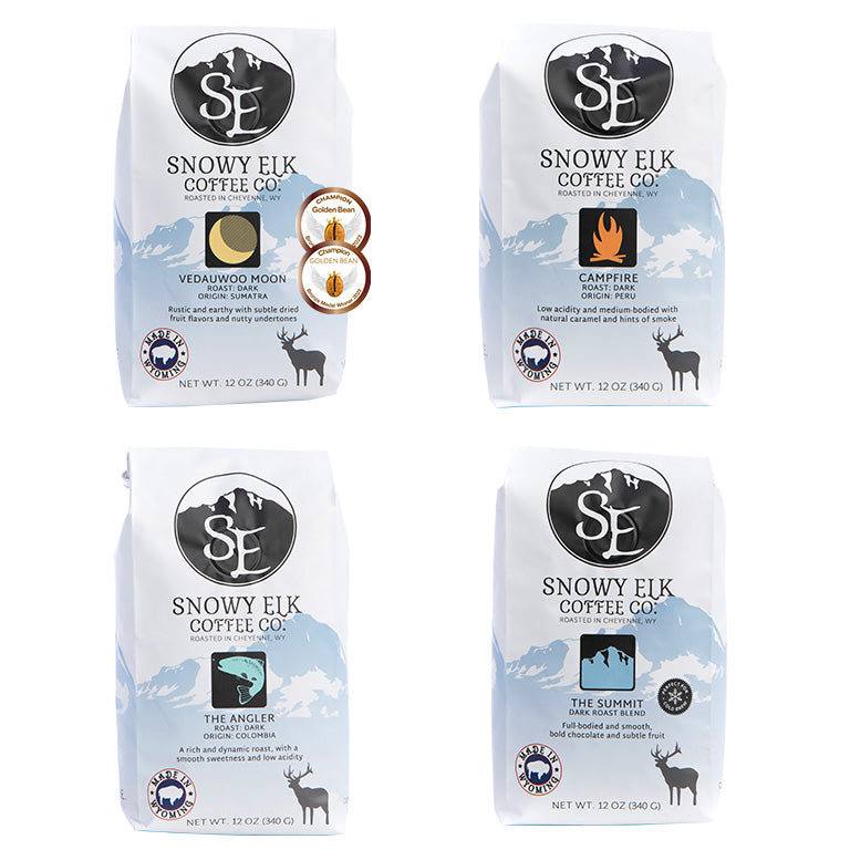 Four white and blue bags of dark roasted coffee with Snowy Elk branding