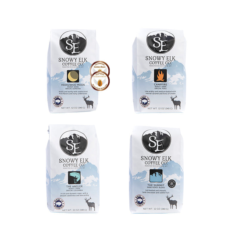 A set of four Snowy Elk Coffee Co. bags of coffee, featuring different dark roasts including 'Campfire' from Peru, 'The Angler' from Colombia, and 'Vedauwoo Moon' from Sumatra.