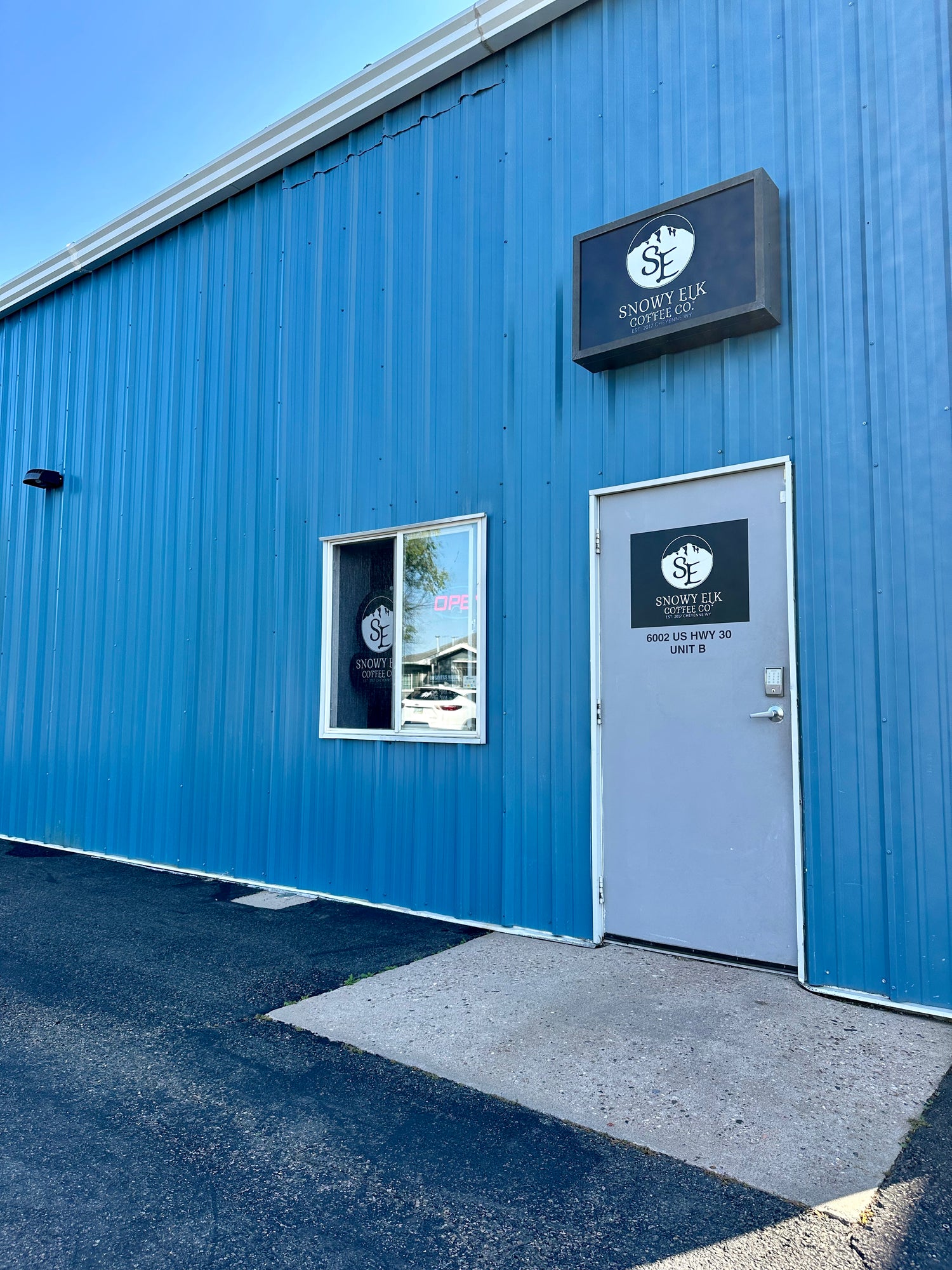 A blue warehouse with a sign that says Snowy Elk Coffee Co