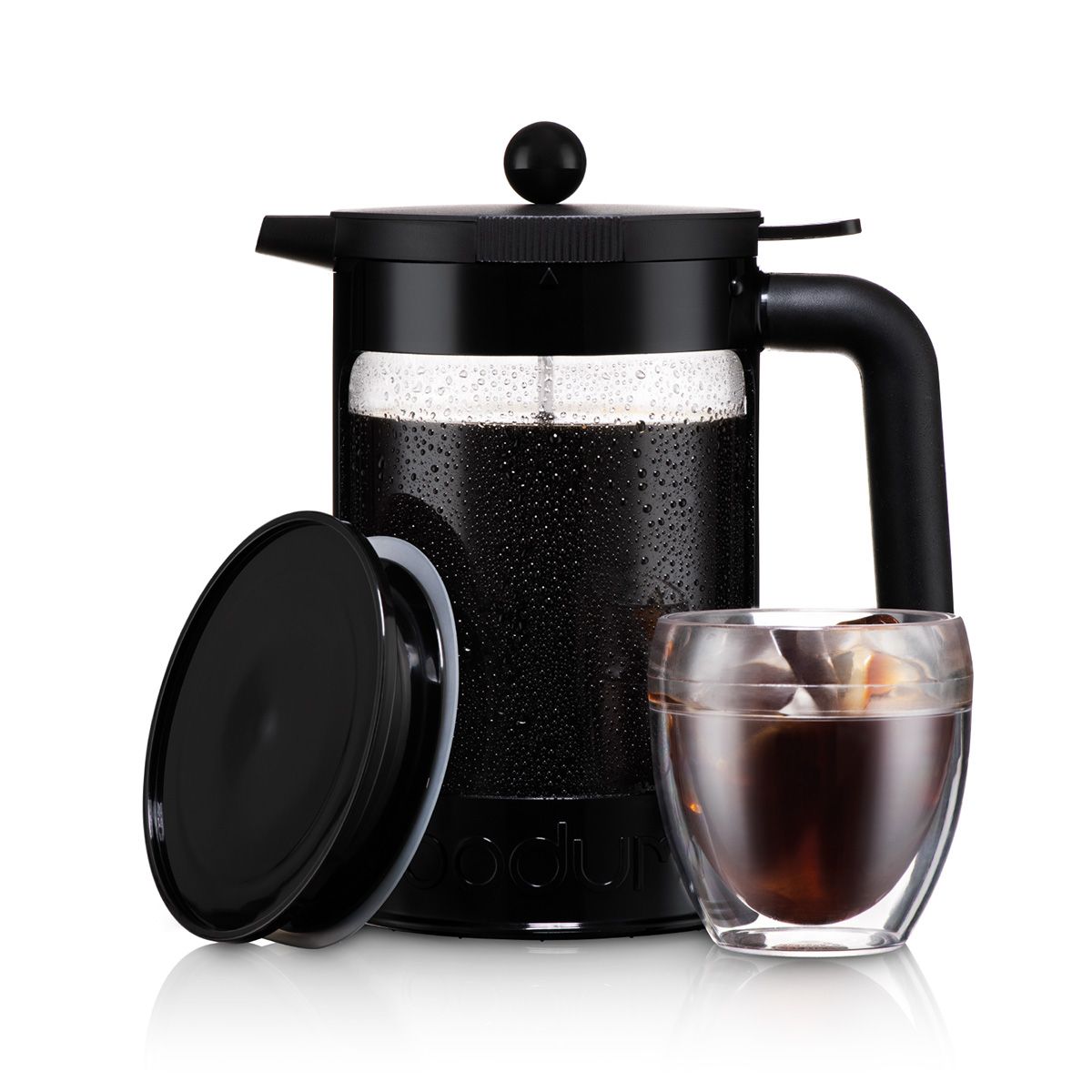 Black cold brew coffee maker with a glass of iced coffee on a white background