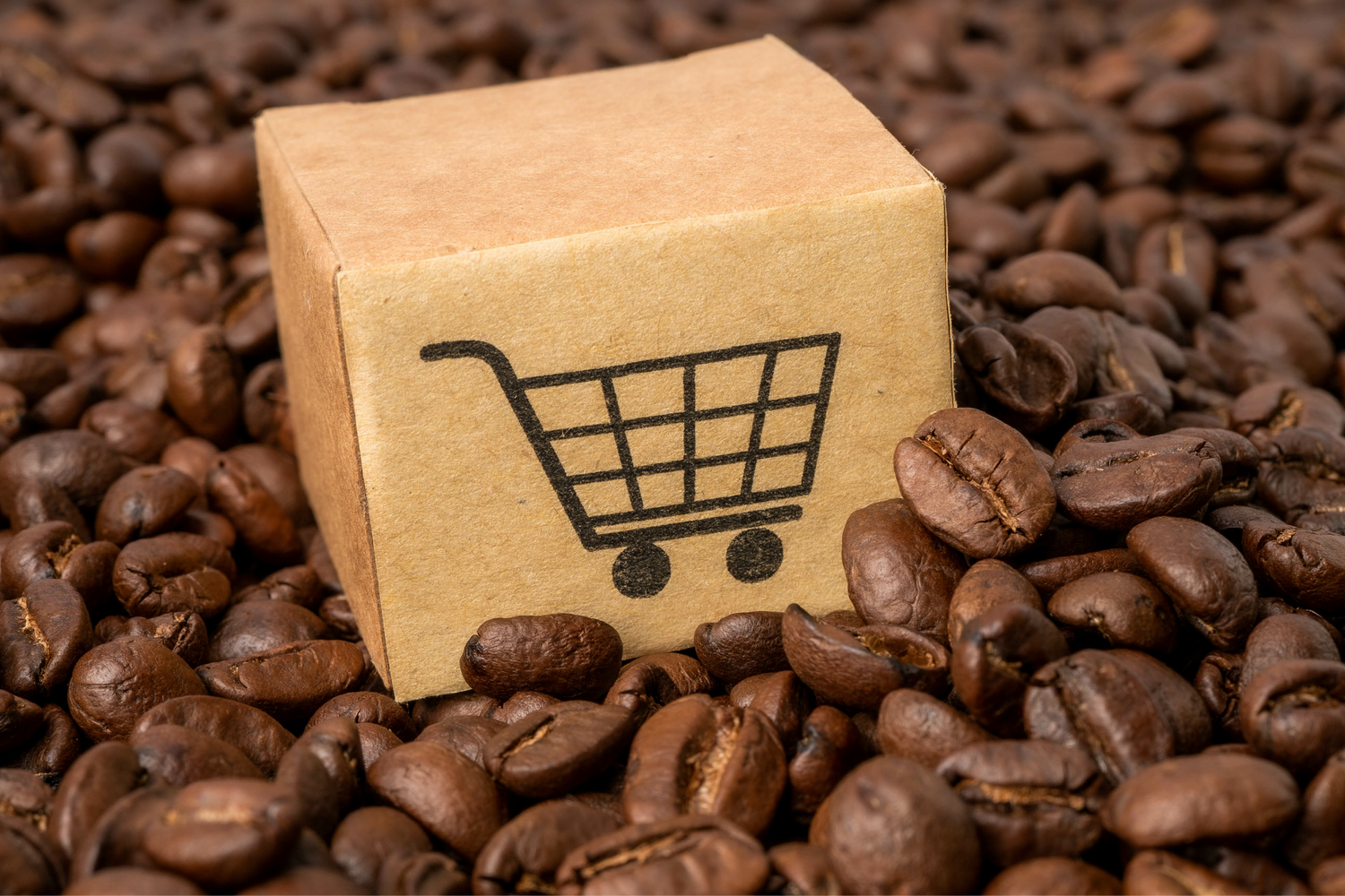 A brown box with a shopping cart on it sitting in a pile of coffee beans