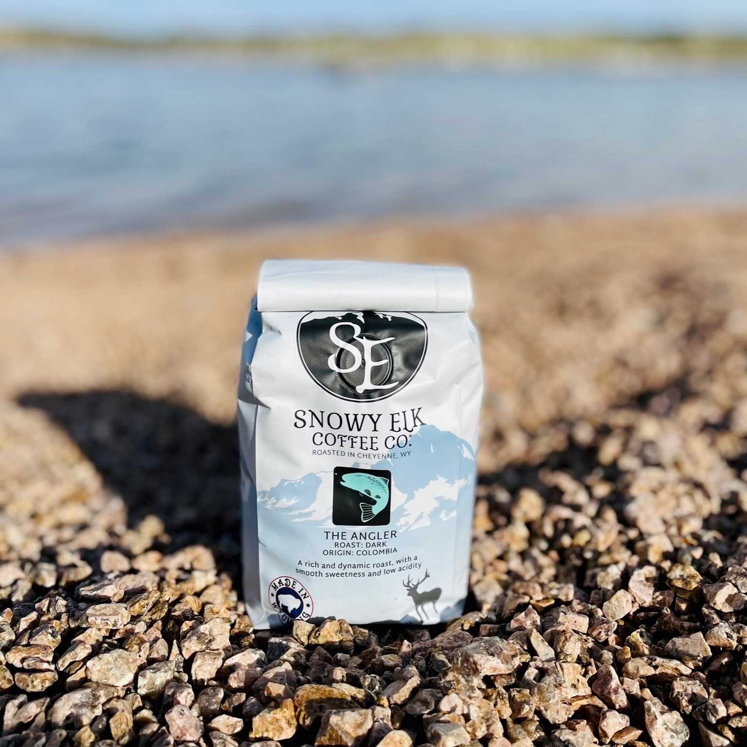 A bag of The Angler coffee on a bed of rocks in an outdoor setting