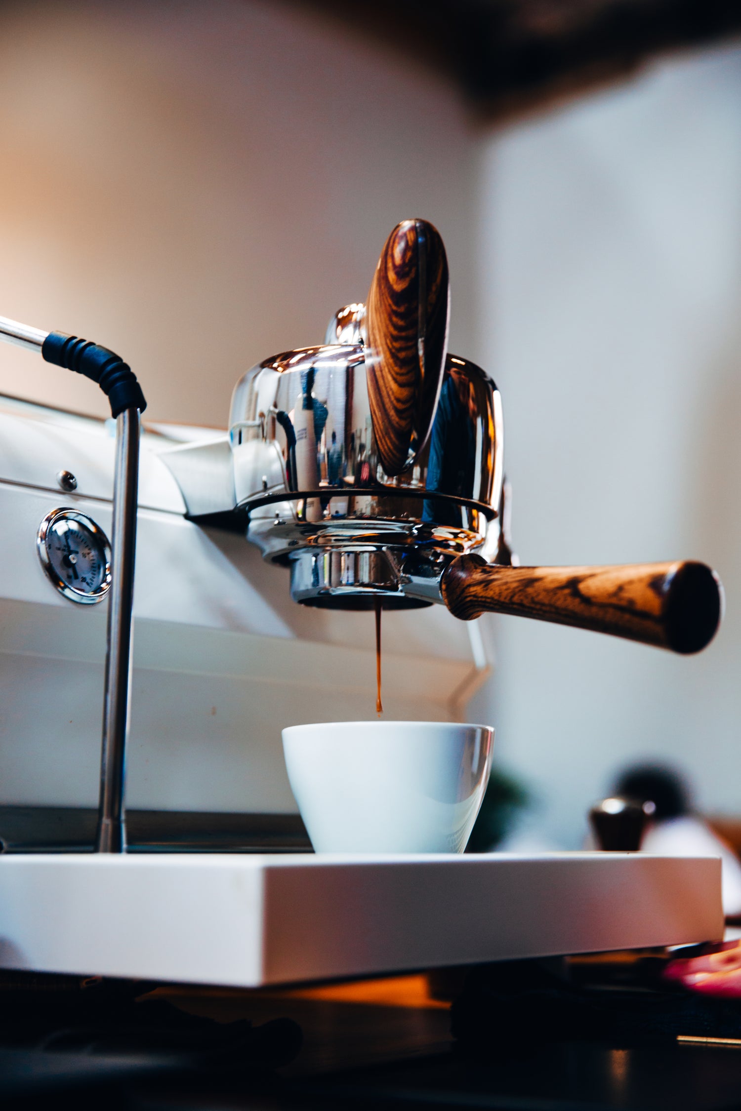 An espresso machine with wooden handle dripping espresso