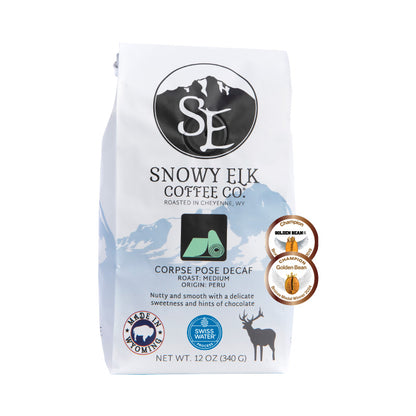 A bag of Snowy Elk Coffee Co. Corpse Pose Decaf coffee with a label showing a mountain and a deer, indicating the product is a medium roast decaffeinated coffee from Peru.