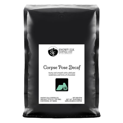 A bag of Snowy Elk Coffee Co. Corpse Pose Decaf coffee with a label showing a mountain and a deer, indicating the product is a medium roast decaffeinated coffee from Peru.