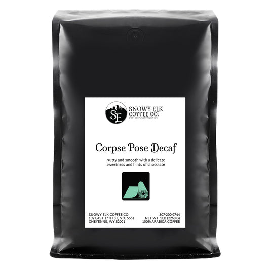 A bag of Snowy Elk Coffee Co. Corpse Pose Decaf coffee with a label showing a mountain and a deer, indicating the product is a medium roast decaffeinated coffee from Peru.