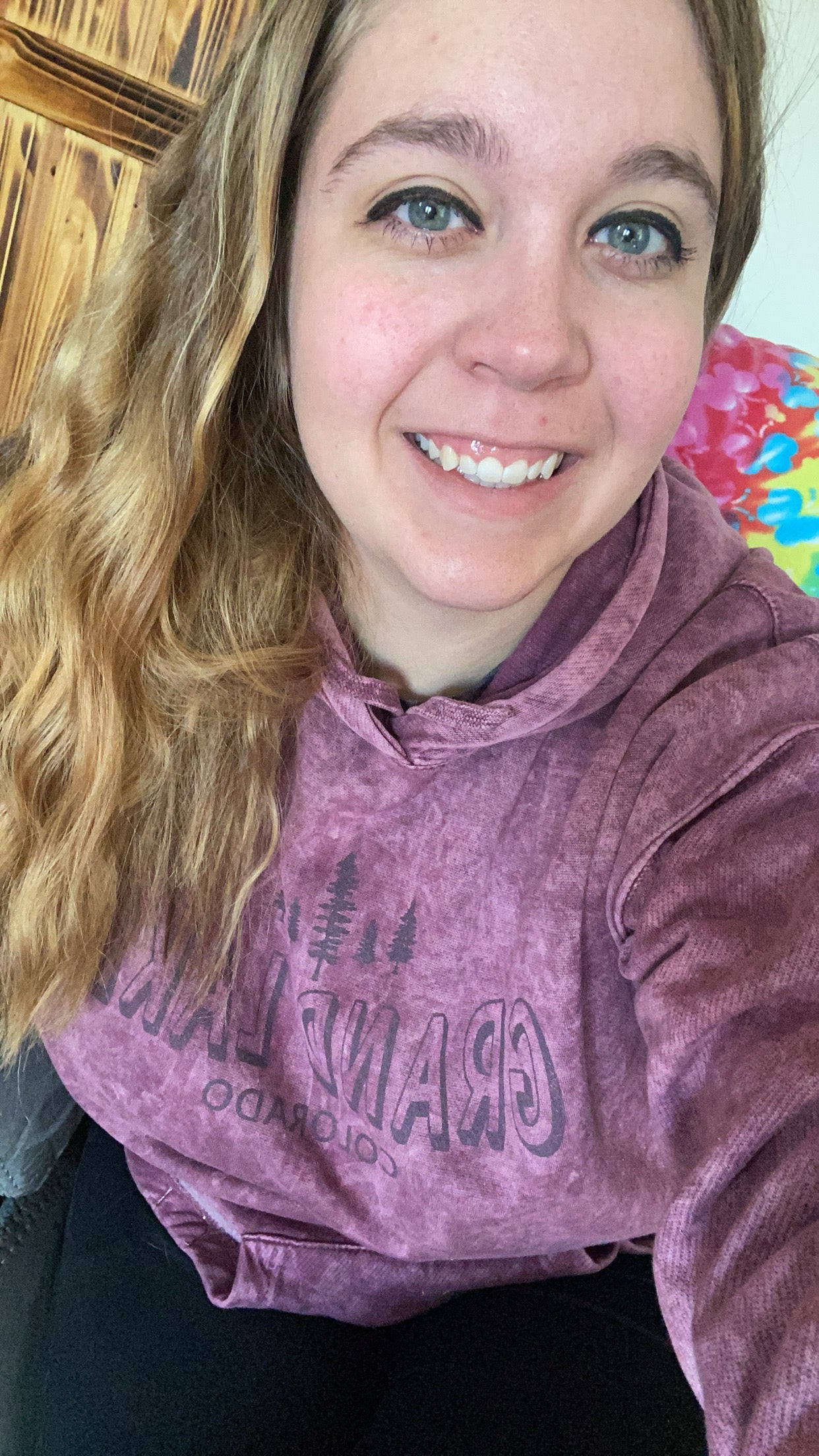Person wearing a purple hoodie with text, sitting on a colorful couch.