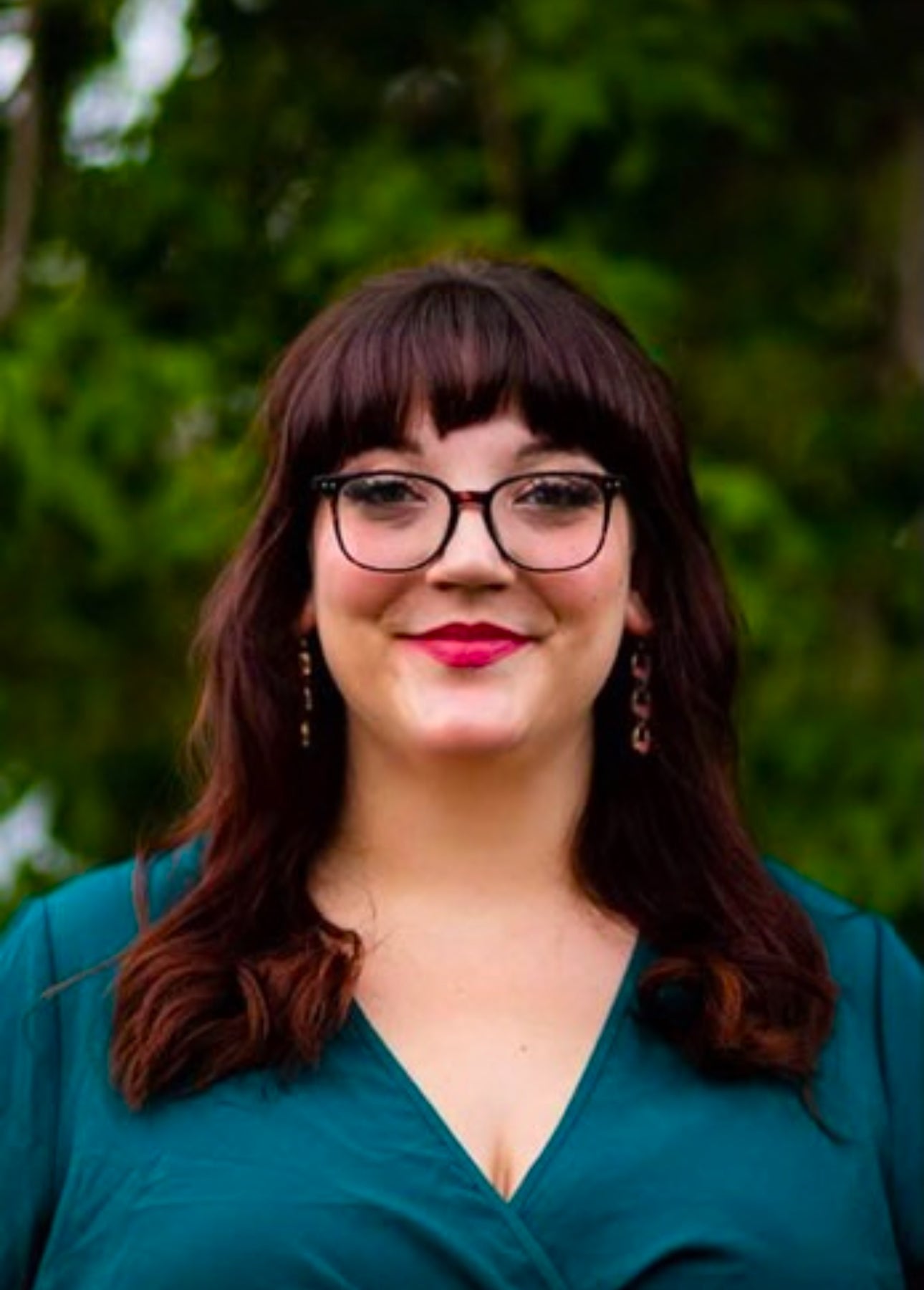 A woman with dark hair and glasses in an outdoor setting