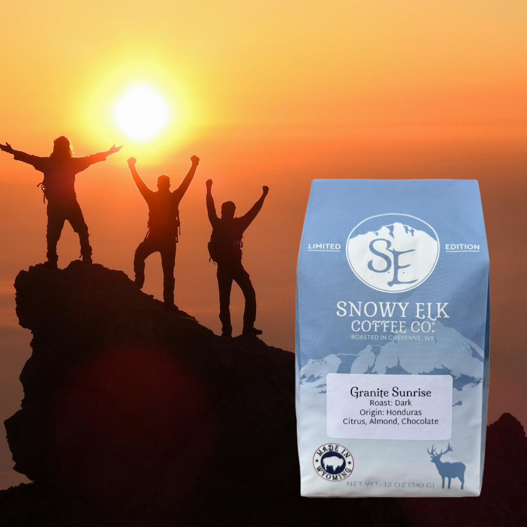 A bag of Granite Sunrise coffee is shown in the foreground against a dramatic sunset background with three silhouetted hikers celebrating on a mountain peak.