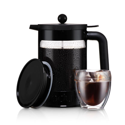 Black cold brew coffee maker with a glass of iced coffee on a white background