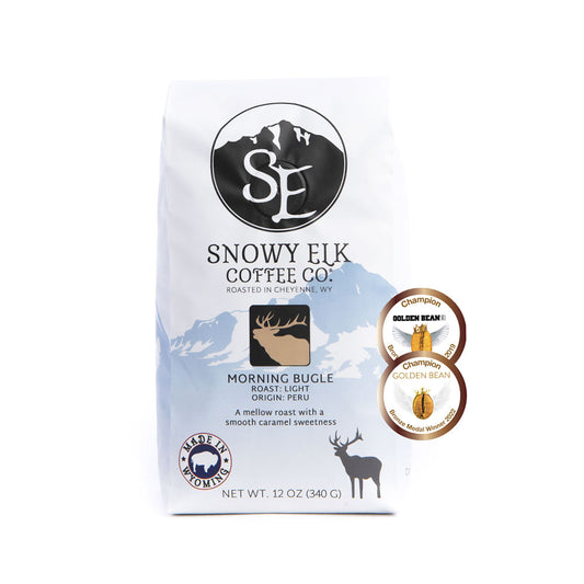 Packaging of Snowy Elk Coffee Co. Morning Bugle, showing a bag of light roast coffee with a deer logo and award badges. Packaging of Snowy Elk Coffee Co. Morning Bugle, showing a bag of light roast coffee with a deer logo and award badges.