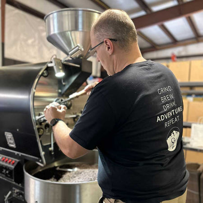 A man wearing glasses standing near a coffee roaster