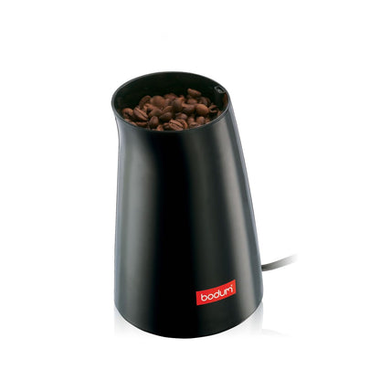 A small black grinder with whole coffee beans inside on a white background